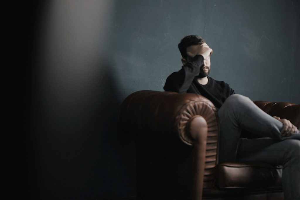 Εικόνα ανθρώπου με παρενέργειες από έλαιο CBD κανναβιδιόλη που κάθεται στον καναπέ.